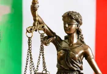 Una statua della giustizia con la bilancia, davanti al tricolore italiano